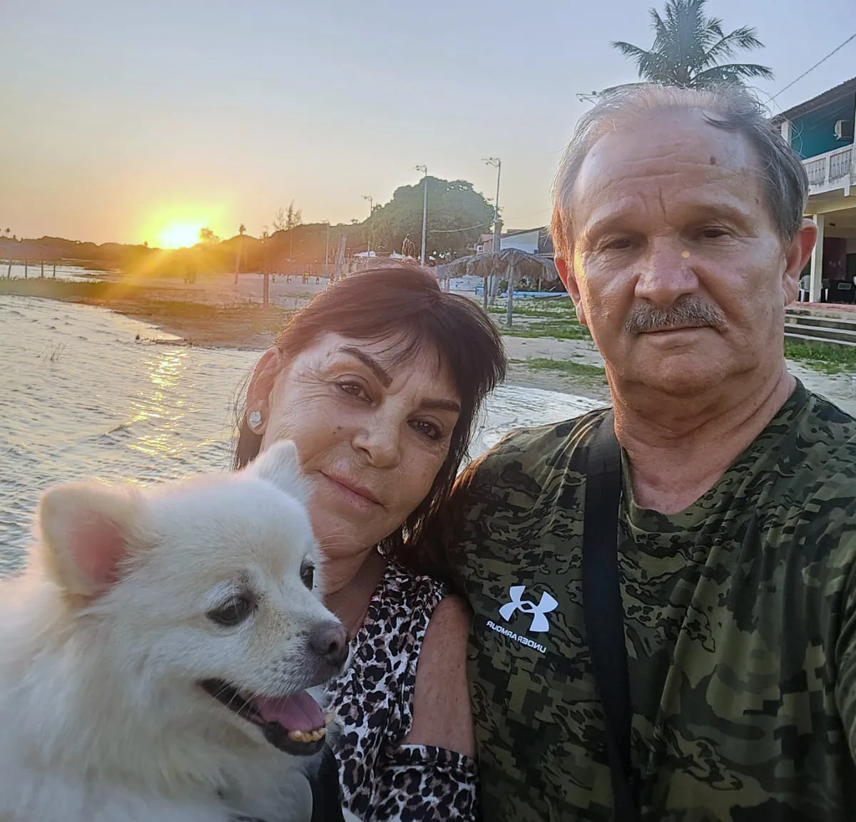 Renato e Vera com o cachorrinho durante uma viagem ao pôr do sol